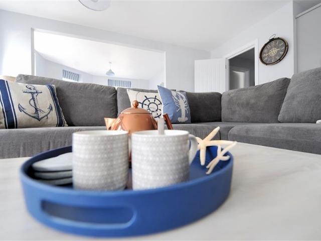 Coffee table décor out of focus in front of grey sofa in beach themed living room