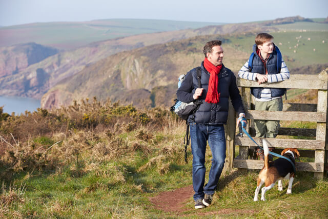 Father and son on walk with dog on a coastal path