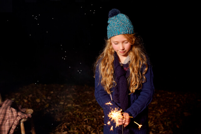 Young girl holding sparkler outside at night