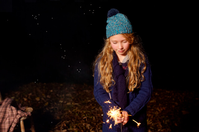 Young girl holding sparkler outside at night