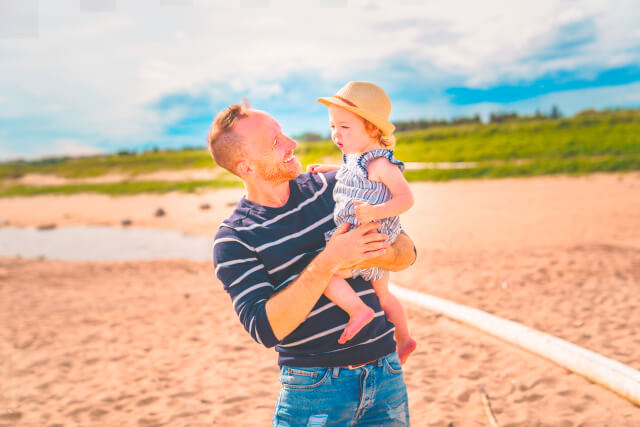 Father holding daughter on Sandy Beach, Lyme Regis