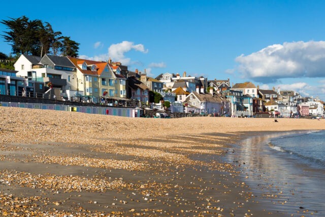 A close up of the sand on the beach at Lyme Regis, with the town in the background